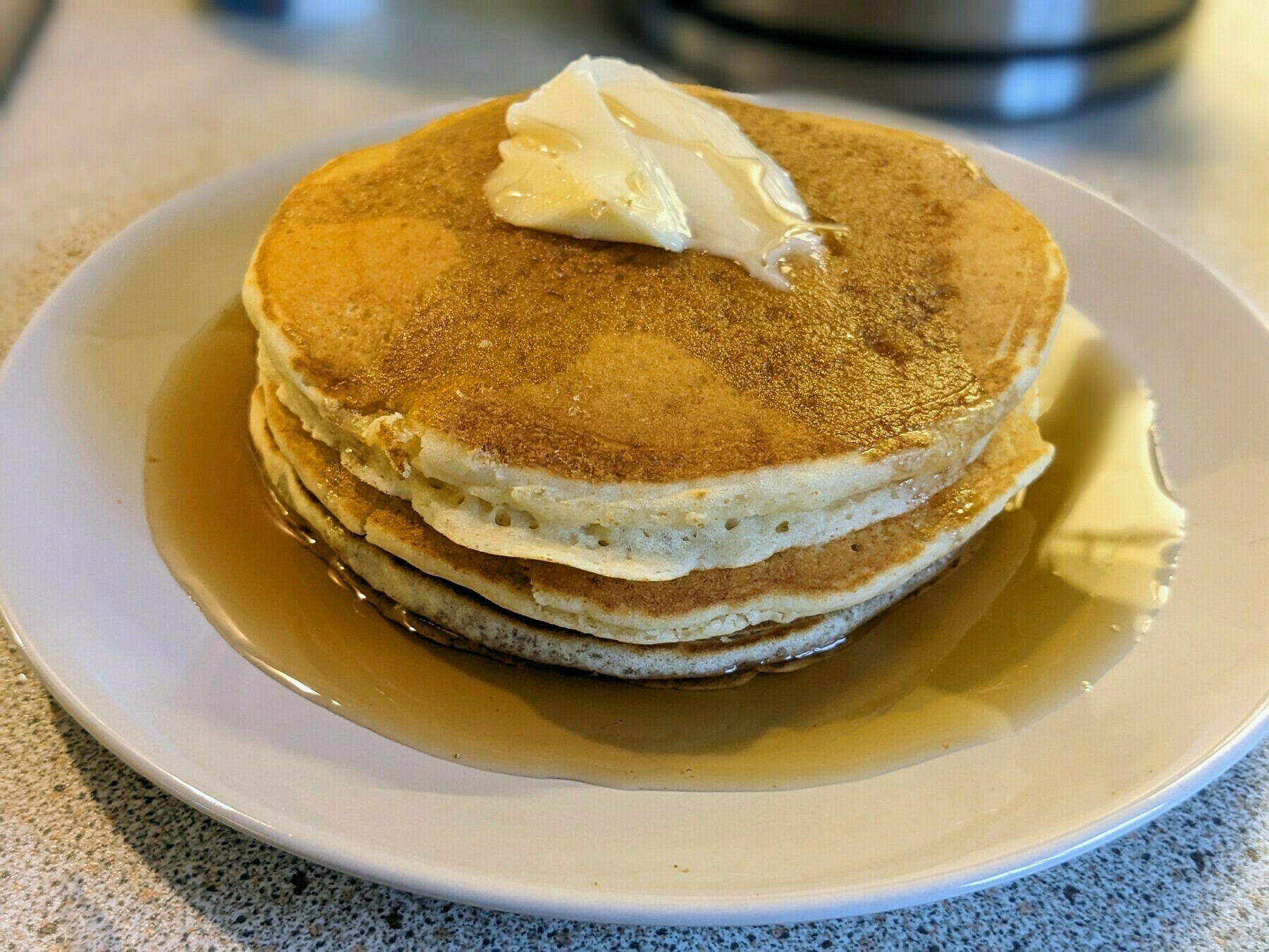 Stack of pancakes on a plate with maple syrup 